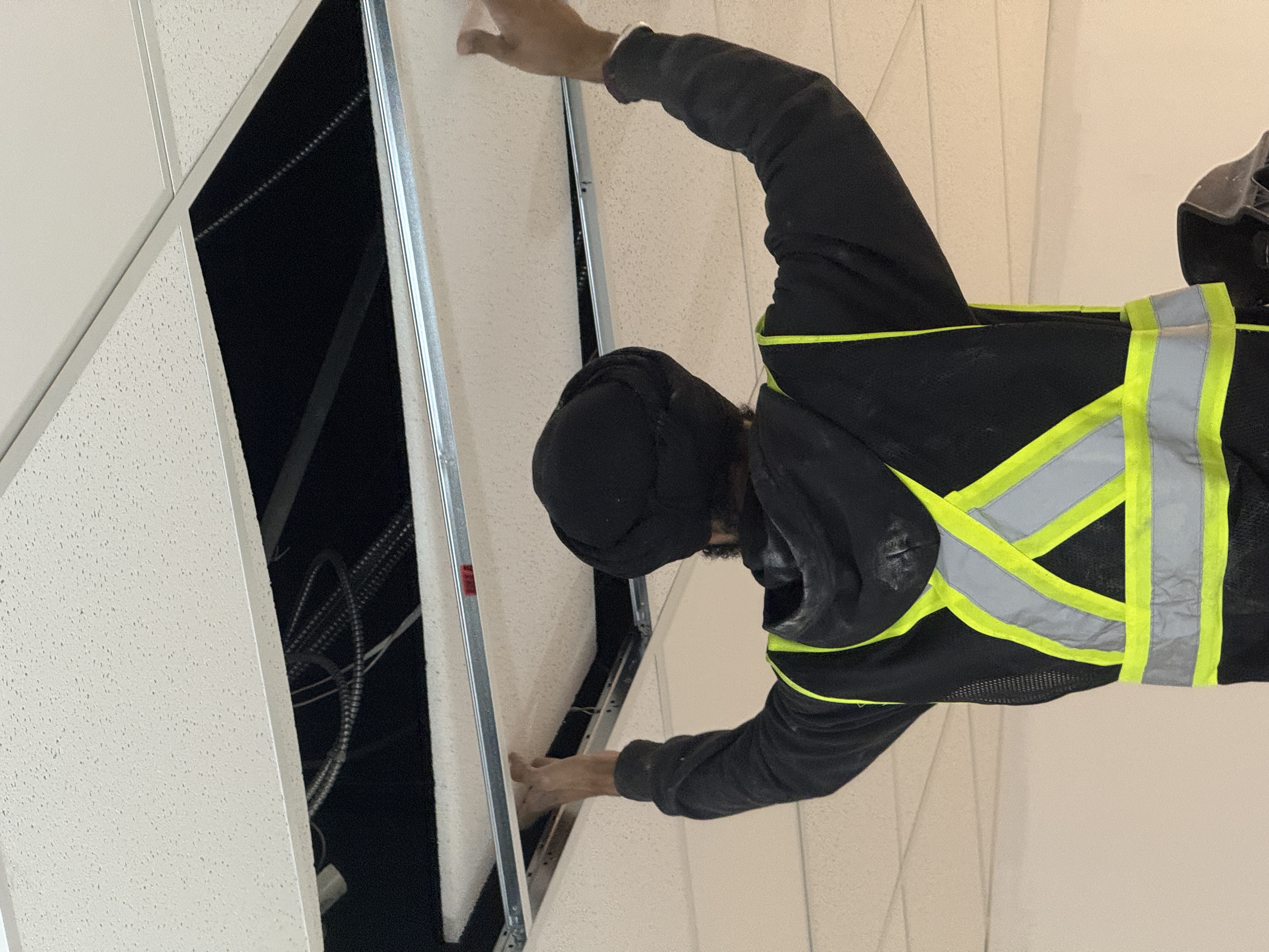 Acoustic ceiling tile being installed into a T-bar grid