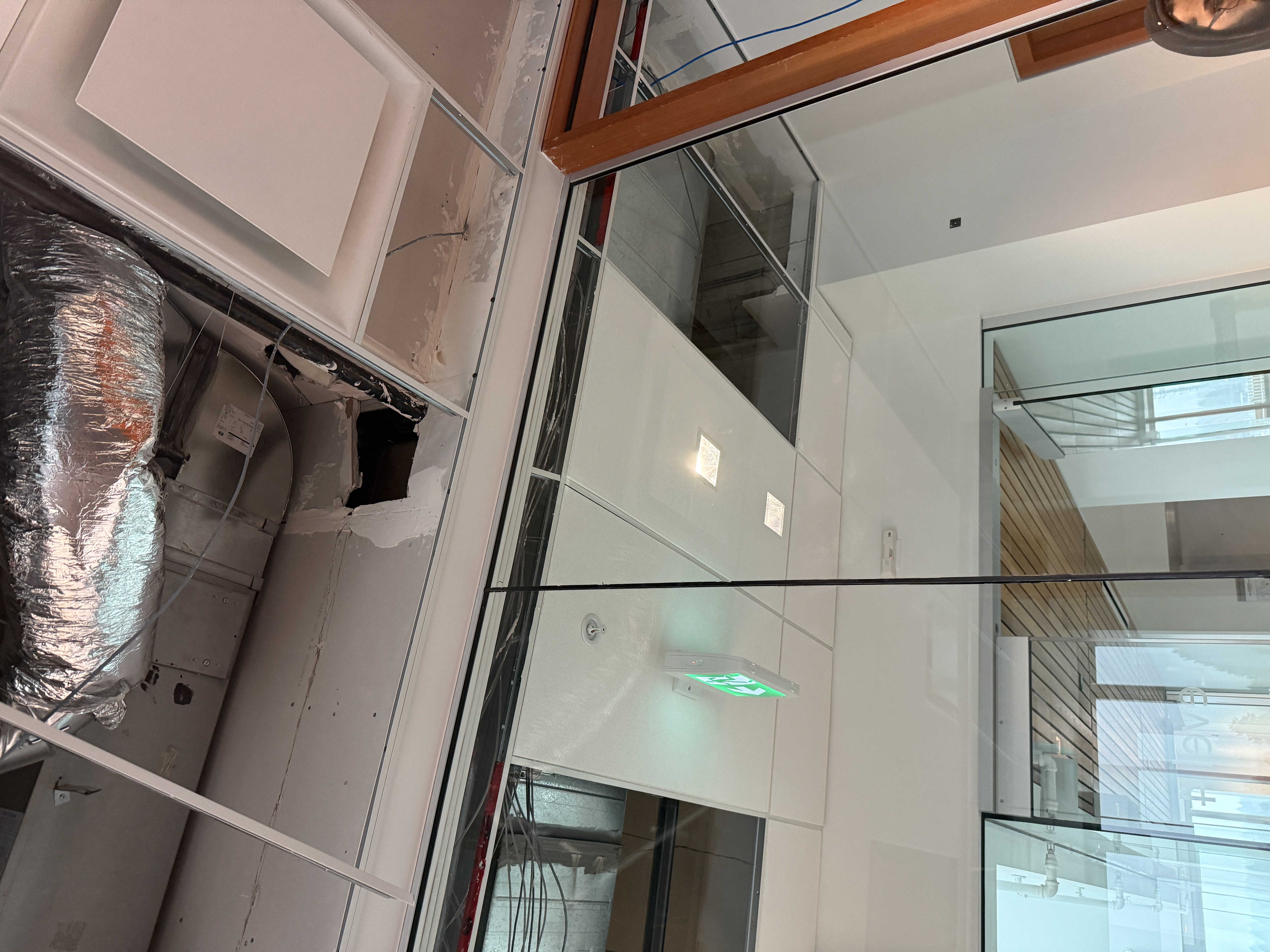 Existing T-bar ceiling being reconfigured around a new glazed wall
